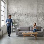 Fototapeta betonowa z motywem roślinnym na wymiar zastosowana w salonie w stylu loft z betonową podłogą i stalowymi oknami.